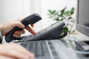 a person using a telephone to dial a number on a keyboard