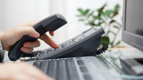 a person using a telephone to dial a number on a keyboard