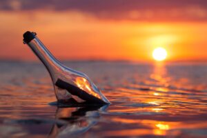 a bottle in the water with a sunset in the background