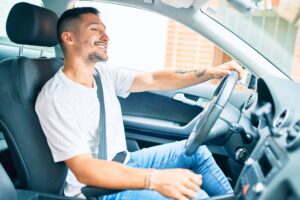 a man smiling while driving a car