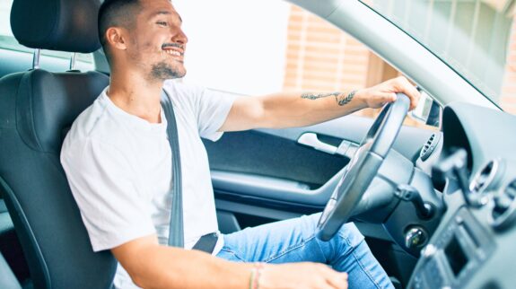 Young hispanic man smiling happy driving car. a man smiling while driving a car