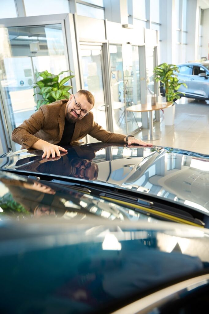 Man Smiles And Strokes The New Car