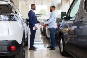 auto showroom manager shaking hands with young man