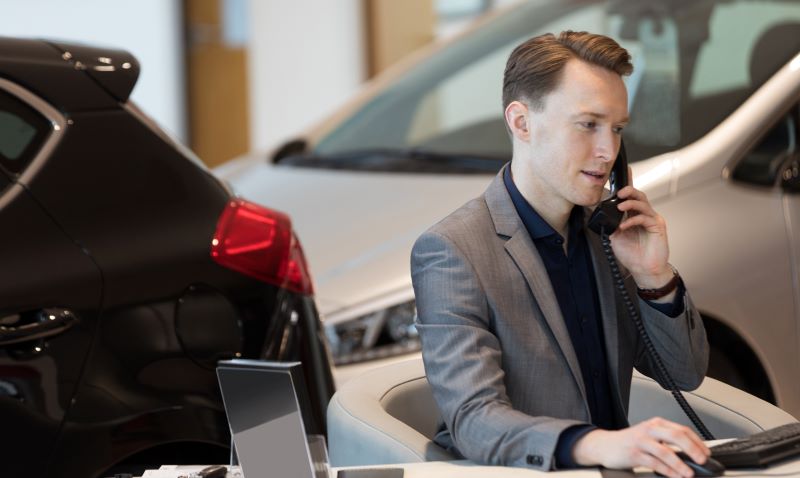 Car Salesman Talking Onphone In Showroom