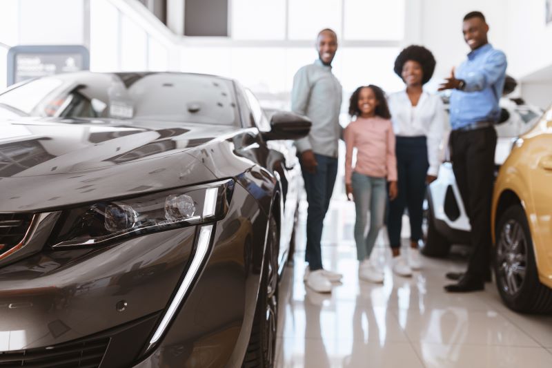 Salesman Helping American Family To Find Perfect Car